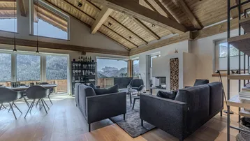 Geräumiger Wohn-Essbereich mit Holzbalkendecke, Kamin und Panoramafenstern mit Bergblick.