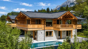 Modernes Chalet mit Holz- und Steinfassade, Balkonen, Infinity-Pool und Bergblick in alpiner Umgebung.