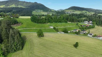 Luftaufnahme einer ländlichen Landschaft mit grünen Hügeln und vereinzelten Häusern.