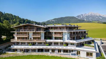 Modernes Mehrfamilienhaus in alpiner Umgebung mit Balkonen und Bergblick.