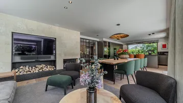 Gemütlicher Wohnbereich mit Kamin, großem Sofa und Blick auf den Essbereich und die moderne Küche.