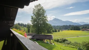 Balkon mit Holzboden und weitem Blick über grüne Wiesen und Berge.