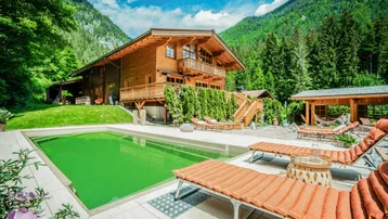 Luxuriöses Holzchalet mit großem Außenpool, Sonnenterrasse und Garten in idyllischer Berglandschaft.