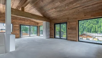 Geräumiger, unmöblierter Innenraum mit Holzwänden und -decke, großen Fenstern und Bergblick.