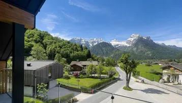 Panoramablick vom Balkon auf die majestätischen Berge und die umliegende grüne Landschaft.