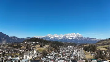 Weitläufige Luftaufnahme einer Stadt im Tal mit schneebedeckten Bergen im Hintergrund.