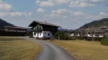 Alpenländisches Haus mit Zufahrt und weitem Blick auf die umliegende Berglandschaft.