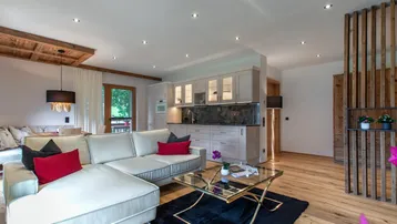 Offener Wohnbereich mit integrierter Küche, Holzboden und gemütlichem Sofa, ideal für gesellige Abende.