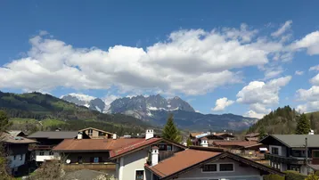 Panoramablick über die Dächer einer Siedlung mit majestätischen schneebedeckten Bergen im Hintergrund.
