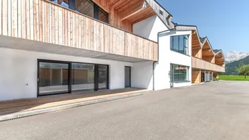 Moderne Architektur mit Holzfassade und großen Fensterfronten, die viel Licht hereinlassen.