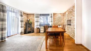 Gemütlicher Wohn-Essbereich mit Kaminofen, Steinwand und Holzboden, ideal für entspannte Abende.