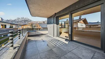 Geräumiger Balkon mit Fliesenboden, Schiebetüren und beeindruckendem Bergblick.
