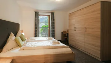Schlafzimmer mit Doppelbett, großem Kleiderschrank und Blick auf die Berge.