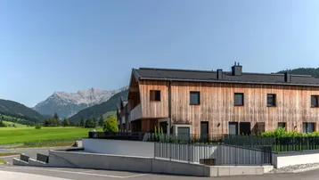Modernes Holzgebäude mit Satteldach und Bergblick in ländlicher Umgebung.