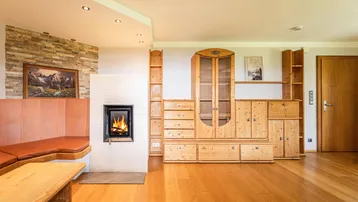 Helles Wohnzimmer mit Kamin, Holzboden und rustikalen Holzmöbeln im alpenländischen Stil.