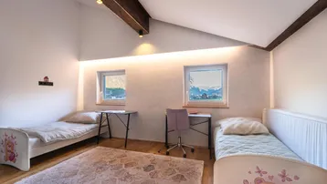 Kinderzimmer mit zwei Betten, Schreibtischen und Blick auf die Berge.