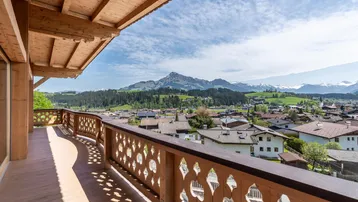 Geräumiger Holzbalkon mit kunstvollem Geländer und weitem Blick auf die umliegende Berglandschaft.