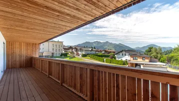 Geräumiger Holz-Balkon mit Bergblick und umliegender Wohnbebauung.