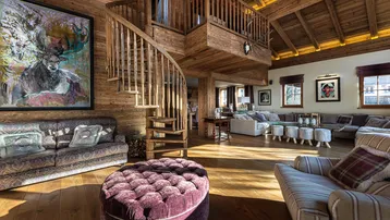 Geräumiges Wohnzimmer im Chalet-Stil mit Holzvertäfelung, Wendeltreppe und gemütlichen Sitzbereichen.
