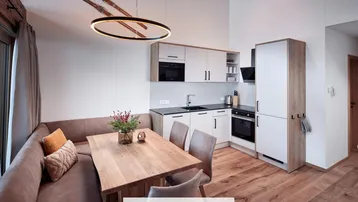 Moderner offener Wohn- und Essbereich mit integrierter Küche, Holzboden und hohen Decken.