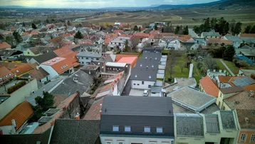 Luftaufnahme einer charmanten Stadt mit vielen Dächern und einer malerischen Landschaft im Hintergrund.
