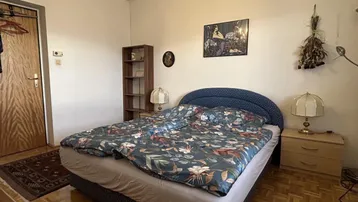 Gemütliches Schlafzimmer mit Doppelbett, Nachttischen und Holzparkettboden.