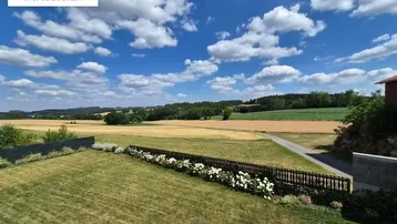Weitläufiger Gartenbereich mit gepflegtem Rasen und malerischem Blick auf die umliegende Landschaft.