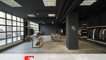 Geräumiger Verkaufsraum mit moderner schwarzer Decke, großen Fenstern und Betonboden, ideal für Einzelhandel.