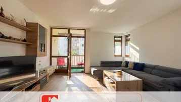 Helles Wohnzimmer mit Holzboden, großem Sofa und direktem Zugang zum Balkon.
