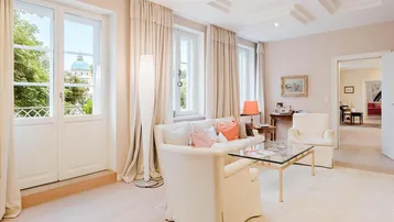 Gemütliches Wohnzimmer mit hellen Möbeln, Parkettboden und Zugang zu einem französischen Balkon.