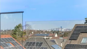 Weitblick von der Dachterrasse über Dächer mit Solaranlagen und die Stadt.