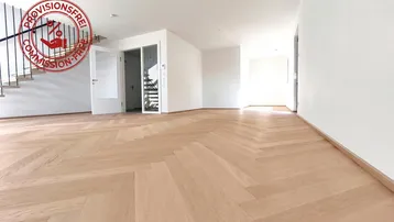 Helles Zimmer mit Fischgrätparkettboden und Treppenaufgang, ideal als offener Wohnbereich nutzbar.