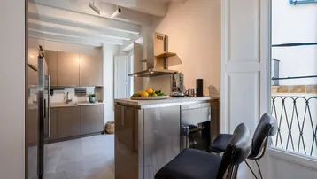 Moderne Küche mit Kücheninsel, glänzenden Fronten und französischem Balkon.