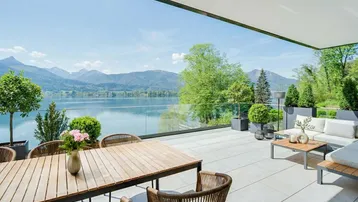 Große, moderne Terrasse mit Esstisch, Lounge-Bereich und atemberaubendem Blick auf den See und die Berge.
