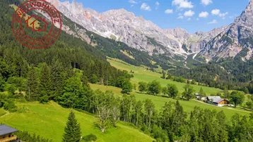 Panoramablick auf die majestätische Berglandschaft mit grünen Wäldern und Wiesen, umgeben von traditionellen Häusern.