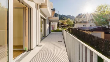 Langer Balkon mit Fliesenboden und Metallgeländer, bietet einen weiten Blick auf die Berge.