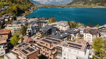 Luftaufnahme einer Wohnanlage am See mit Bergen im Hintergrund.