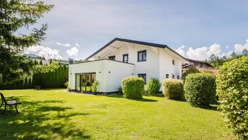 Großer, gepflegter Garten mit weitläufiger Rasenfläche und einem modernen Haus im Hintergrund.