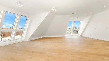 Helles und geräumiges Dachgeschosszimmer mit Holzboden und großen Dachfenstern, ideal für Wohn- oder Schlafbereich.