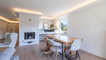 Gemütlicher Essbereich mit Holztisch, modernen Stühlen und einem integrierten Kamin.