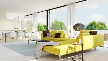 Helles, offenes Wohnzimmer mit gelben Sofas, Essbereich und großen Fensterfronten zum Grünen.