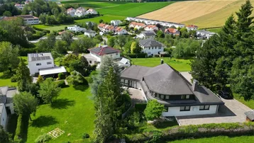 Luftaufnahme eines einzigartigen Hauses mit runder Dachform, umgeben von einem großen Garten und ländlicher Umgebung.