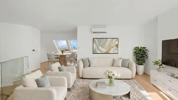 Helles, modern eingerichtetes Wohn- und Esszimmer mit Dachschrägen und stilvollen Möbeln.