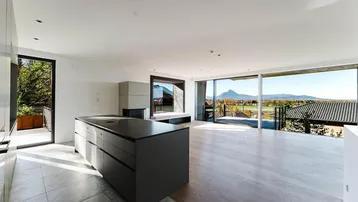 Heller, offener Wohn-Essbereich mit moderner Kücheninsel und beeindruckendem Bergblick.