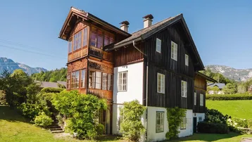 Traditionelles Chalet mit aufwendigen Holzschnitzereien, Balkon und Bergblick in sonniger Lage.