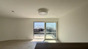 Lichtdurchfluteter Raum mit großen Schiebetüren und weitem Blick auf die Stadt und Berge.