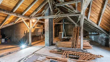 Geräumiger Dachboden mit sichtbaren Holzbalken und Dachschrägen, bereit für den Ausbau.