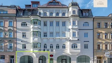 Historisches Gebäude mit eleganter Fassade, großen Bogenfenstern und modernisierten Geschäftsflächen im Erdgeschoss.