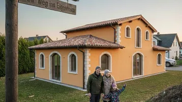 Familie steht vor einem charmanten Einfamilienhaus mit traditioneller Architektur und gepflegtem Vorgarten.