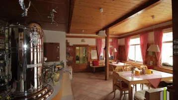 Traditioneller Essbereich mit Holztäfelung, gefliestem Boden und rustikalen Möbeln in alpiner Atmosphäre.